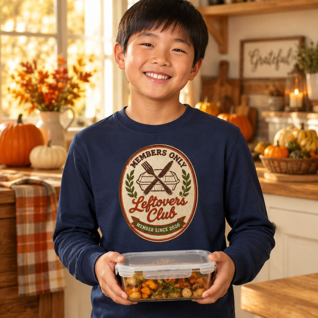 Kid wearing the navy Leftovers Club kids Thanksgiving long sleeve tee with a retro crest graphic