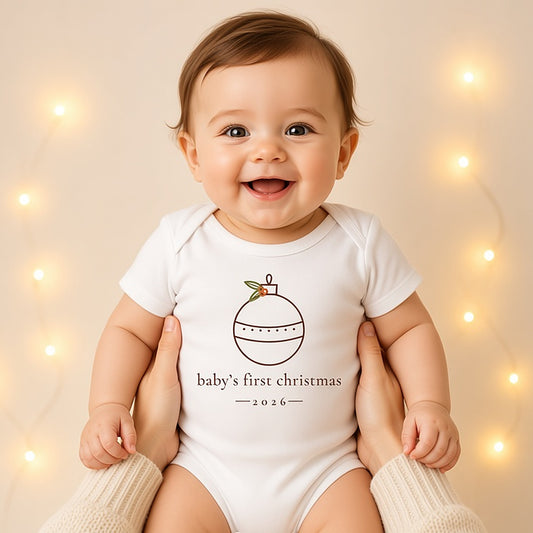 Baby in the minimalist baby's first Christmas 2026 bodysuit in a warm studio holiday portrait