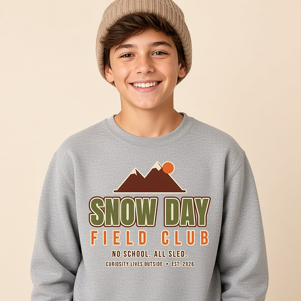 Boy in a beanie wearing the grey bold Snow Day Field Club kids winter sweatshirt