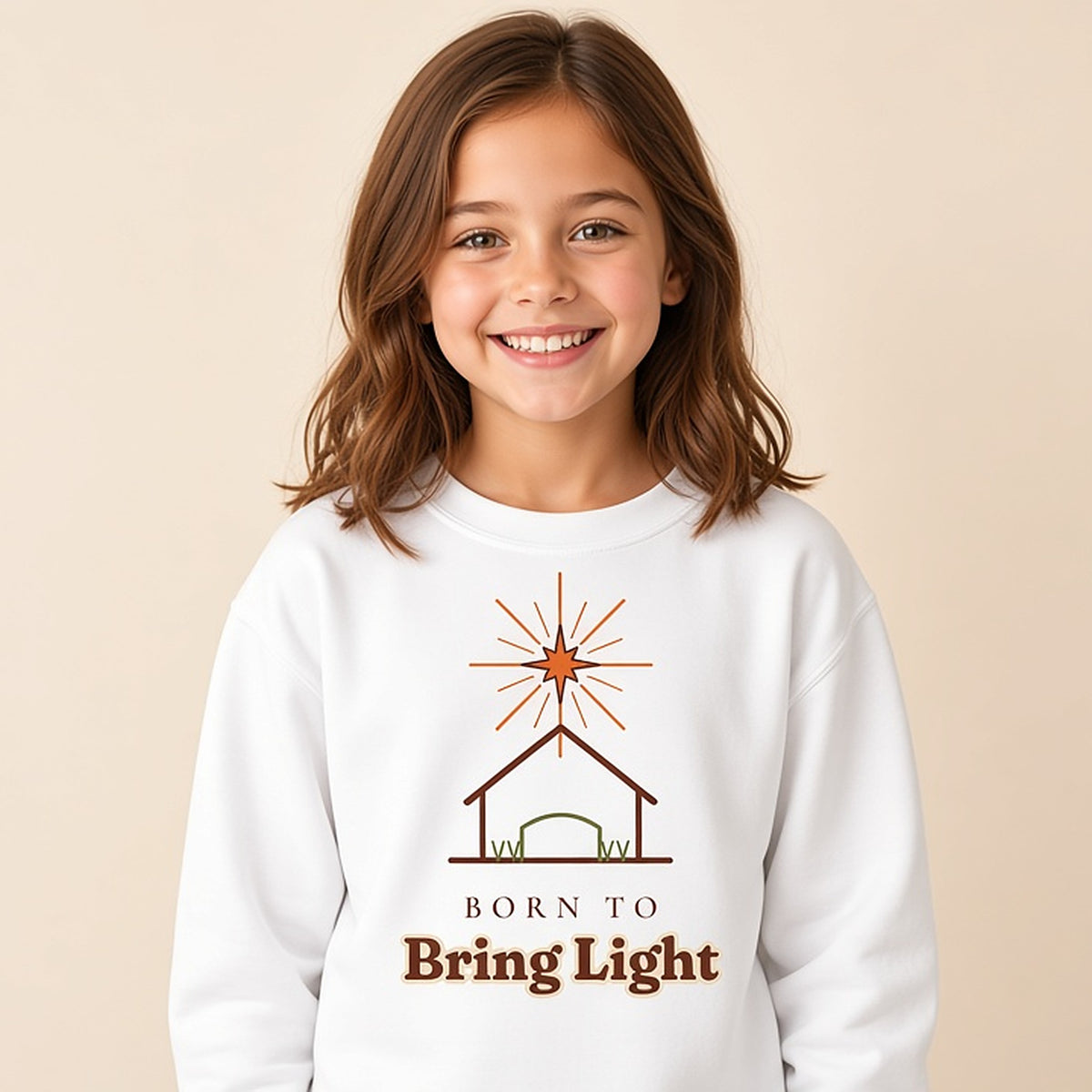 Girl in a white Born to Bring Light kids Christmas sweatshirt with a star over a stable