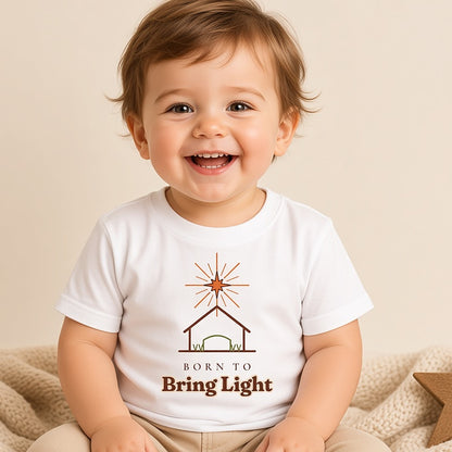 Smiling toddler in the Born to Bring Light star and stable Christmas tee