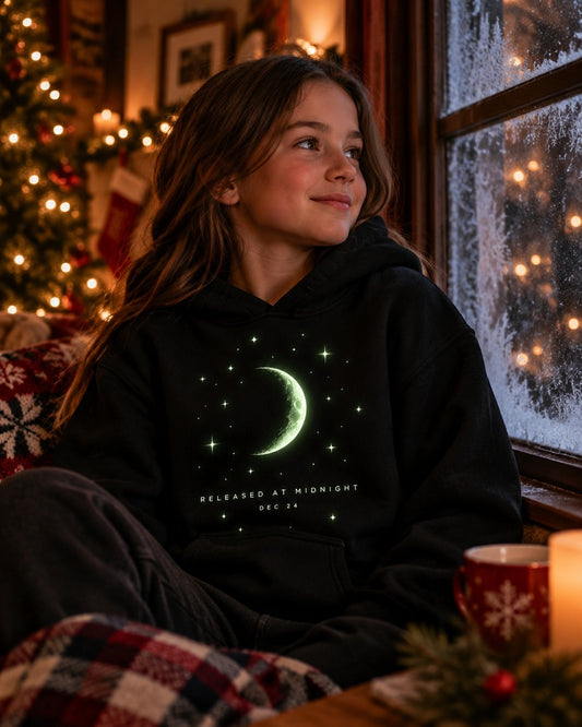 Girl wearing the black Released at Midnight kids hoodie with a glowing crescent moon graphic
