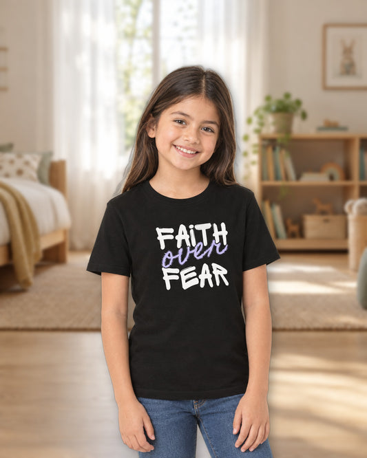 Girl wearing the black Faith Over Fear kids tee in a sunny bedroom