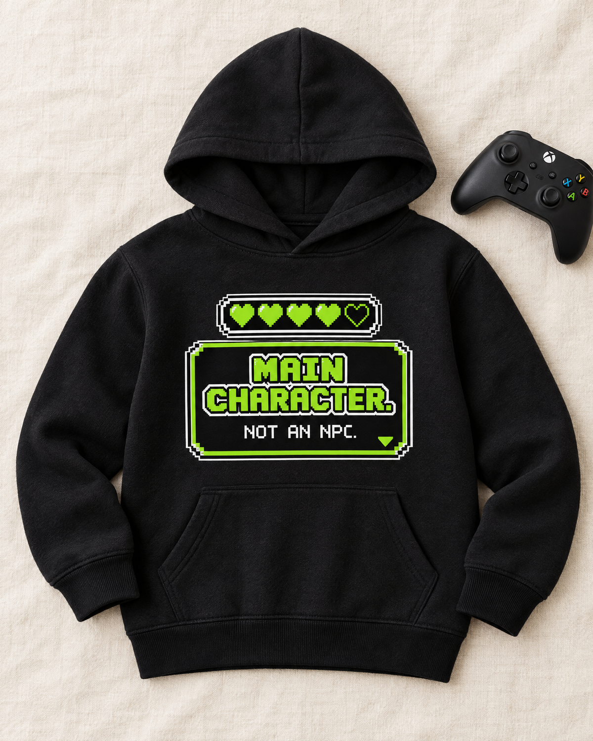 Flat lay of the Main Character Not an NPC kids hoodie with a controller