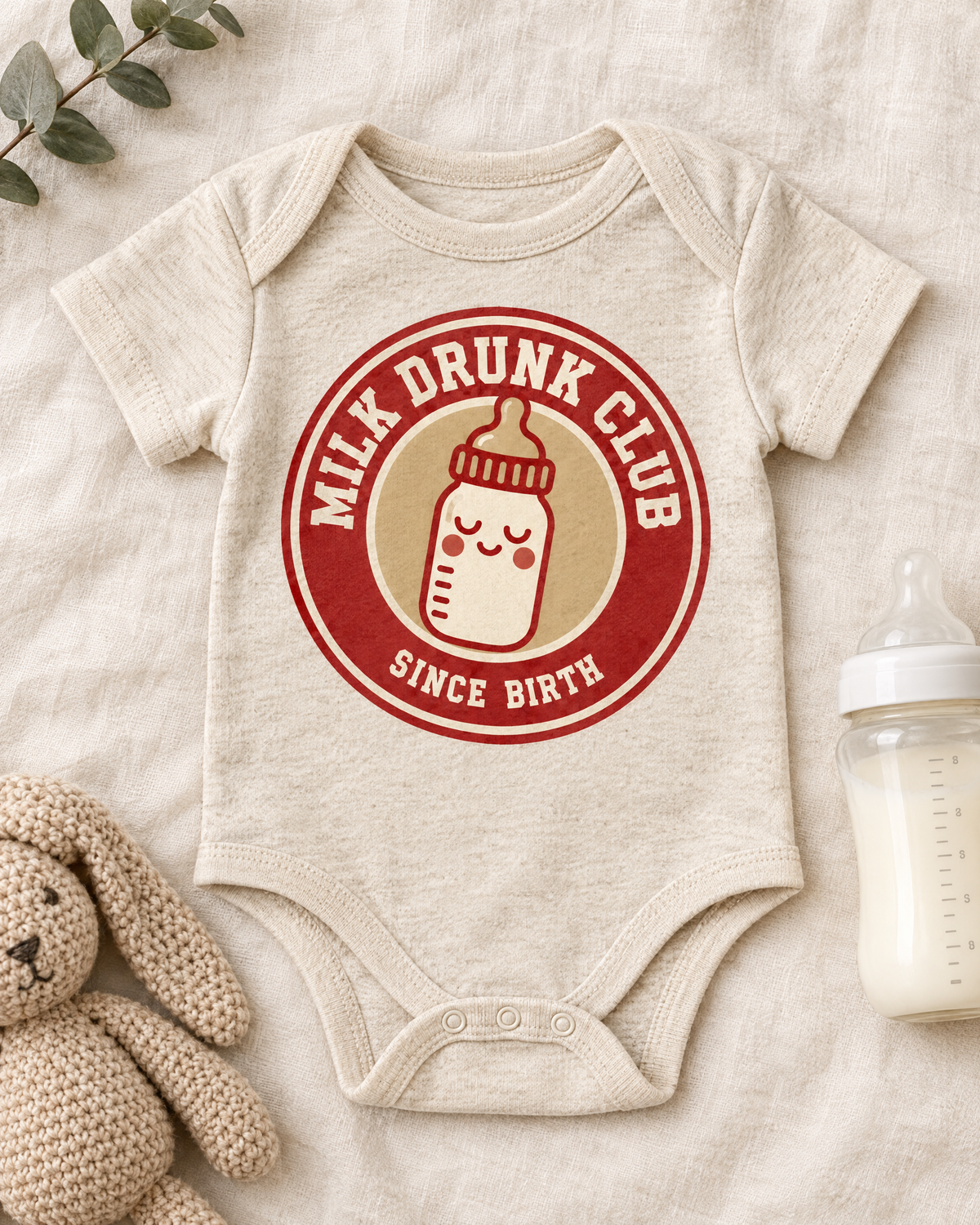 Flat lay of the Milk Drunk Club baby bodysuit with a baby bottle