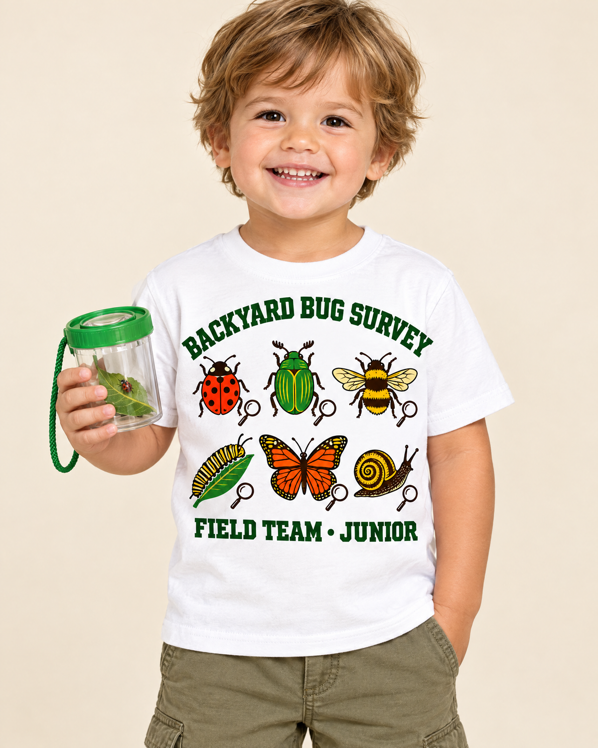 Smiling toddler holding a bug jar wearing the Backyard Bug Survey field guide tee