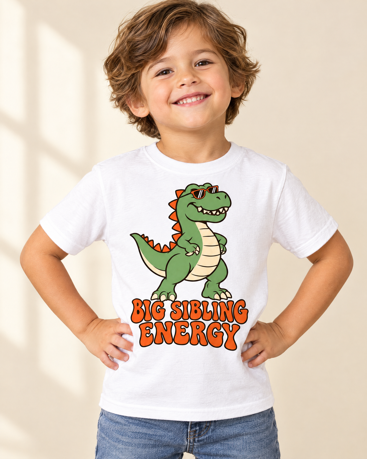 Proud toddler in the Big Sibling Energy dinosaur t-shirt on a cream backdrop