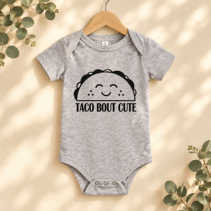 Taco 'Bout Cute Baby Bodysuit in Athletic Heather on a wooden hanger - Cartsy