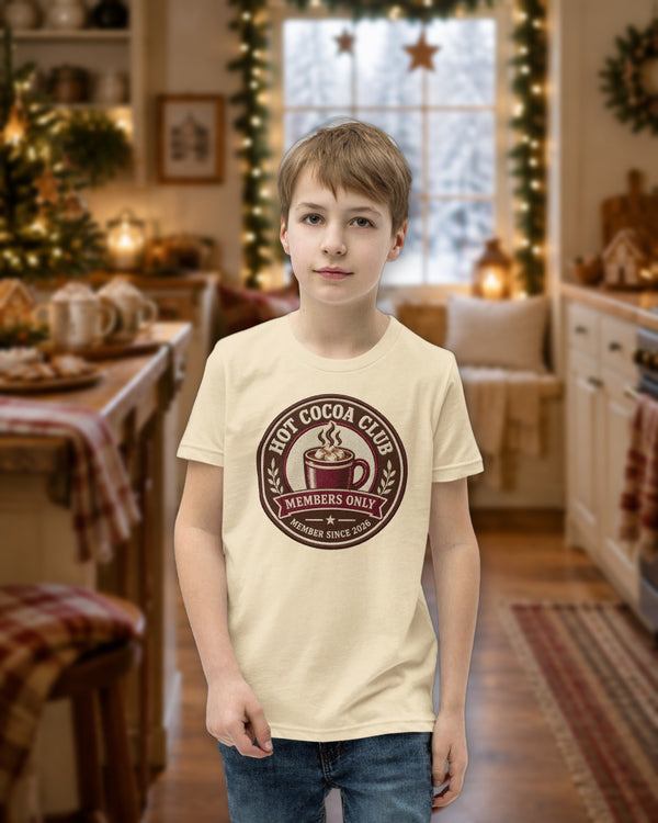 Kid wearing the natural Hot Cocoa Club tee in a cozy Christmas kitchen