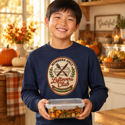 Kid wearing the navy Leftovers Club kids Thanksgiving long sleeve tee with a retro crest graphic
