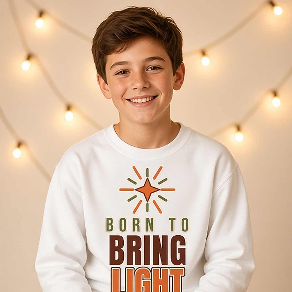 Boy on a stool under string lights in the bold Born to Bring Light crewneck