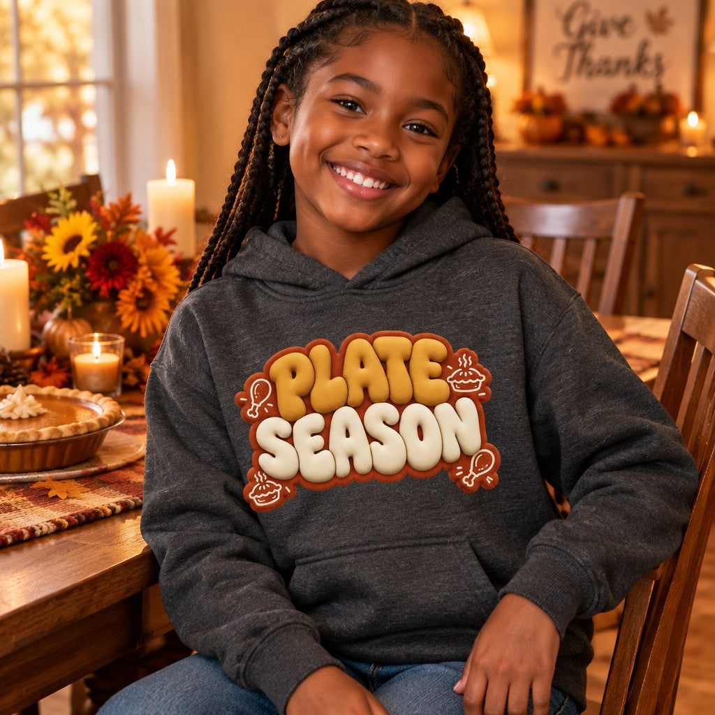Kid wearing the Dark Heather Plate Season kids Thanksgiving hoodie with puffy golden-brown lettering