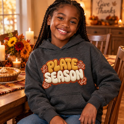 Kid wearing the Dark Heather Plate Season kids Thanksgiving hoodie with puffy golden-brown lettering