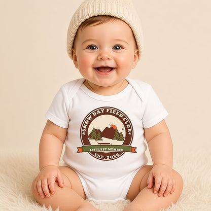 Baby in a knit beanie wearing the white Snow Day Field Club Littlest Member bodysuit