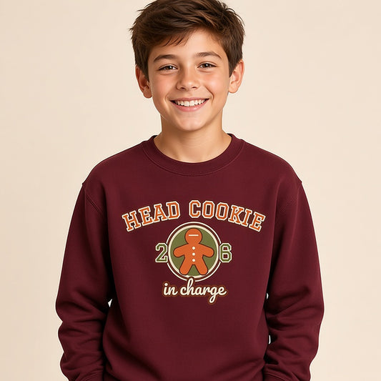 Boy in the maroon varsity Head Cookie in Charge kids Christmas sweatshirt with a gingerbread patch