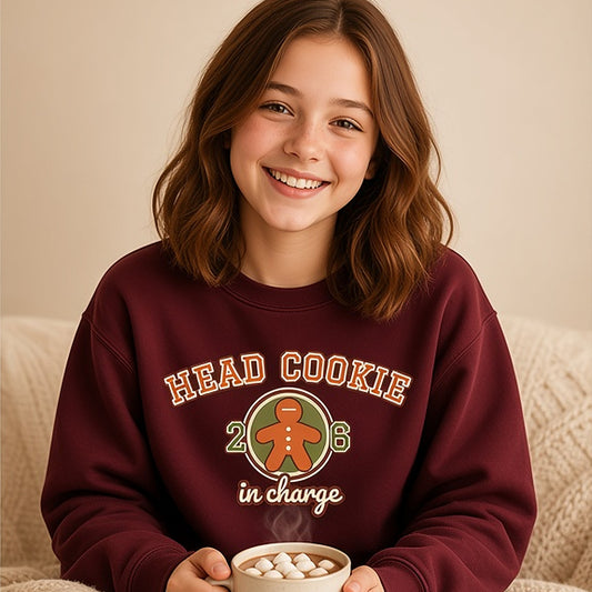 Girl holding hot cocoa in the maroon varsity Head Cookie in Charge kids sweatshirt